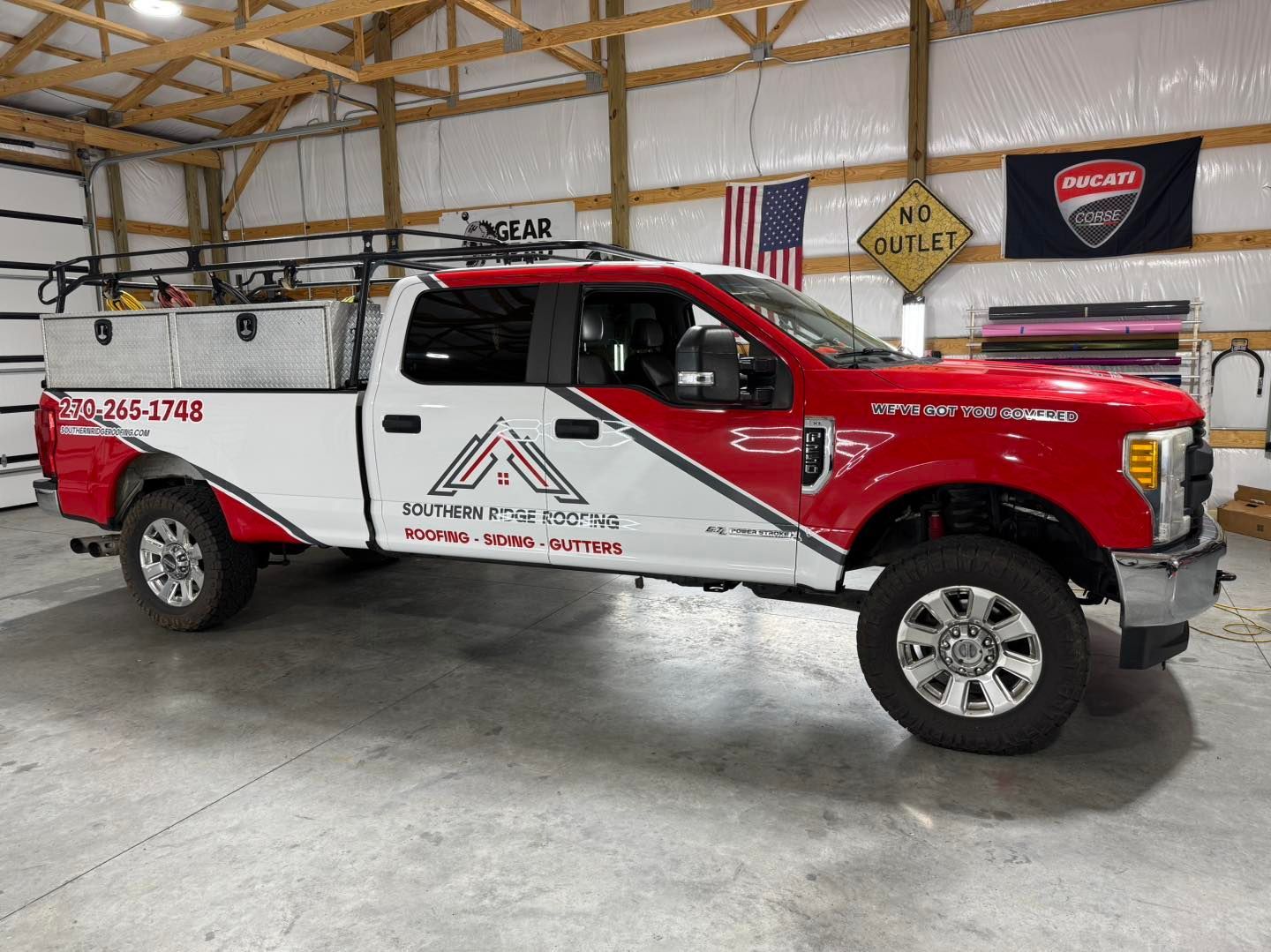 Red and white work truck with logo parked inside a large building.