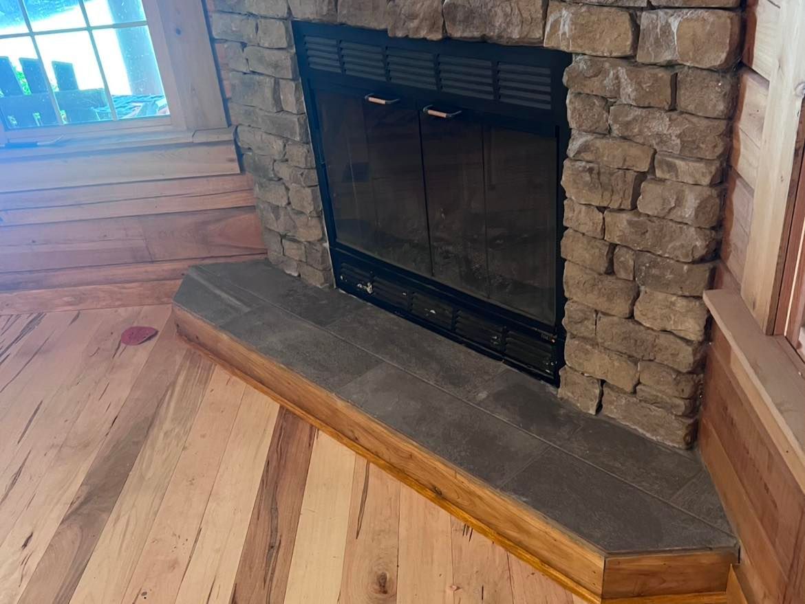 Stone fireplace with gray hearth, on wooden floor.