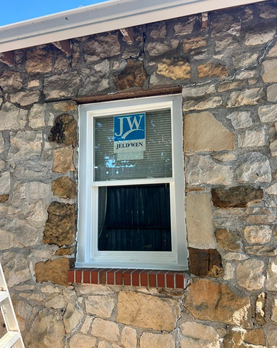 A new white window installed in a stone wall of a building.