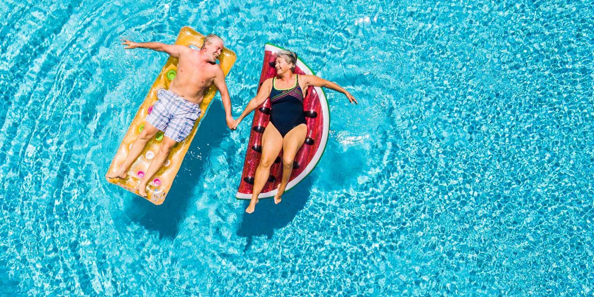 older couple floats on pool floaties