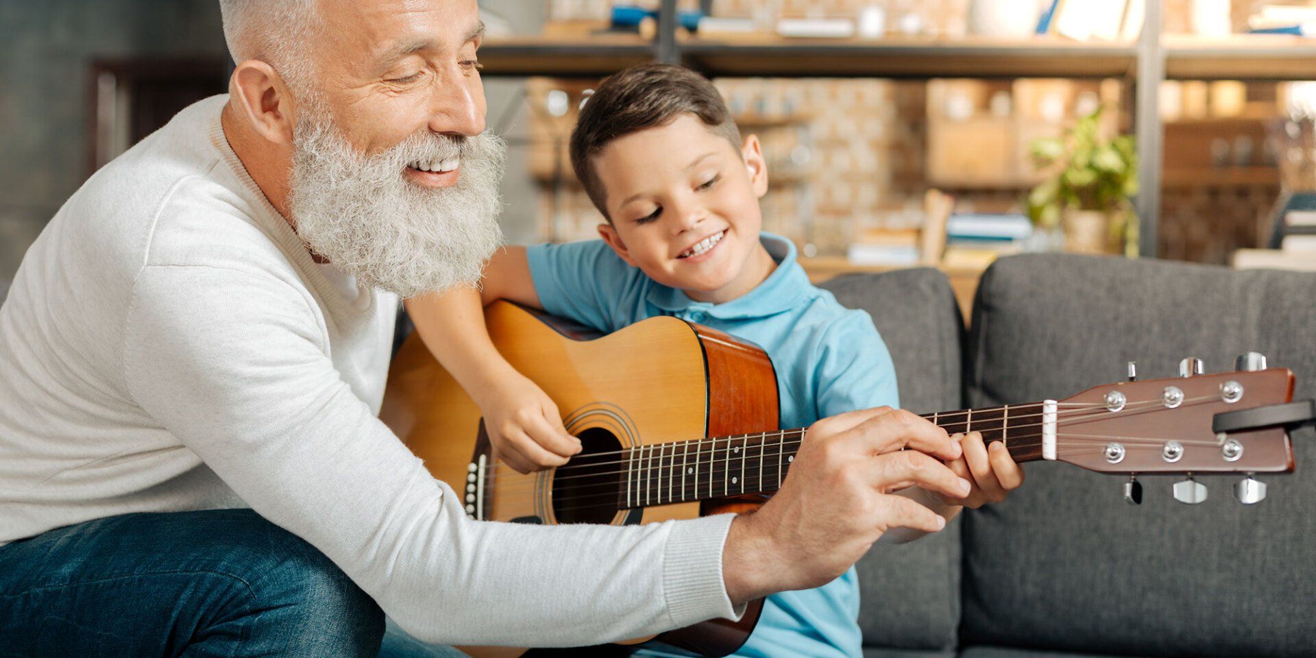 older man teaches kid how to play guitar
