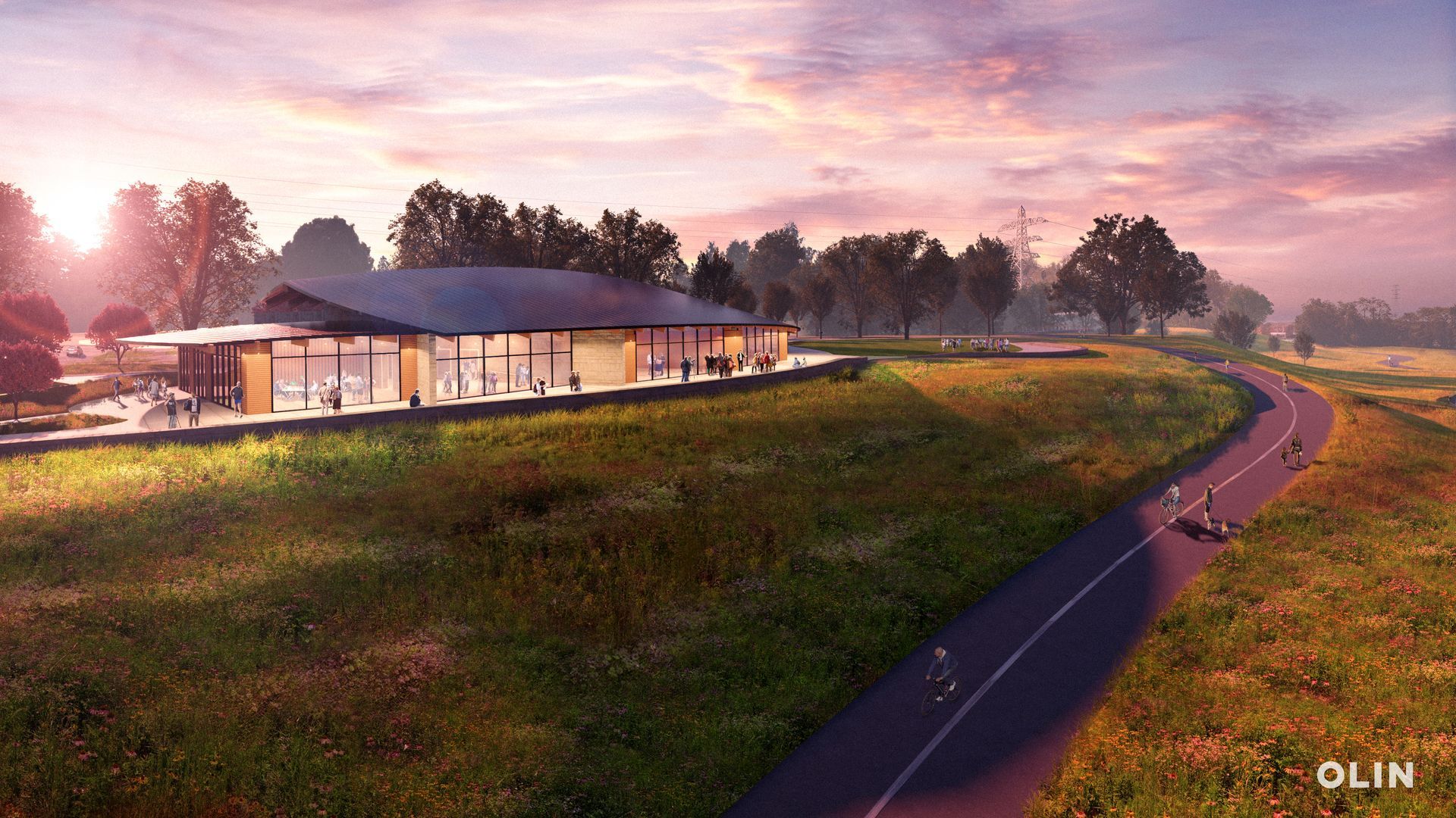 Modern building on a grassy hill next to a paved path with cyclists, at sunset.