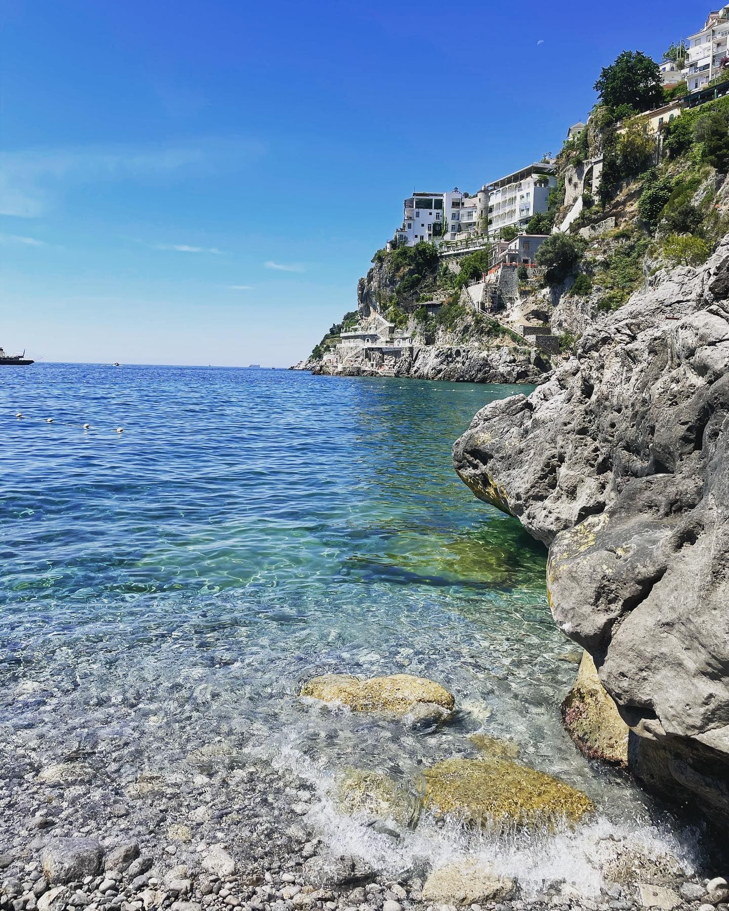 Una costa rocciosa vicino a uno specchio d'acqua con una scogliera sullo sfondo.