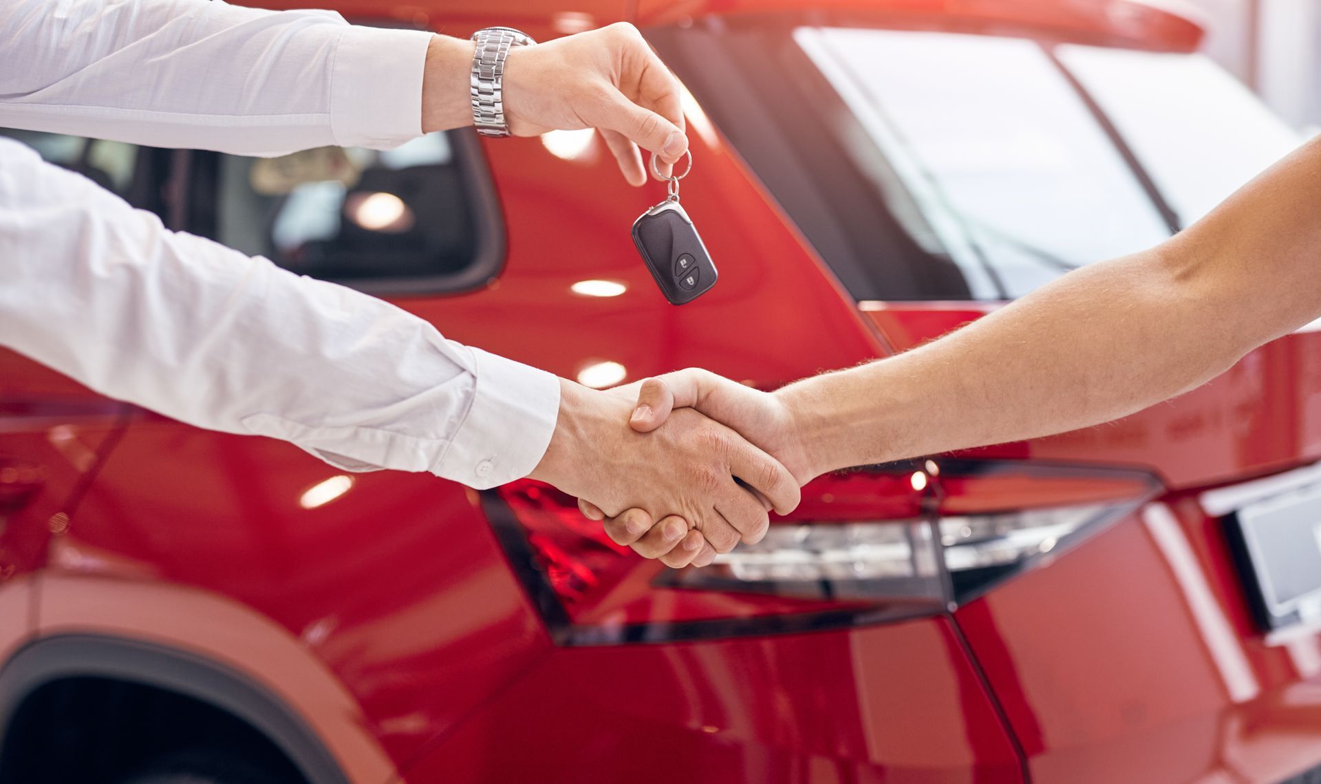 Luxury car rental customer receiving keys during handshake by red premium SUV vehicle. Luxury car rental customer receiving keys during handshake by red premium SUV vehicle.