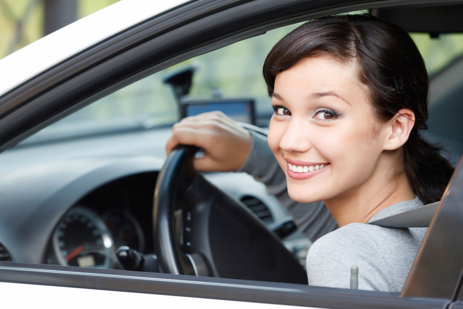 Cute girl sitting in a car, showcasing a fun experience with a friendly car rental service.