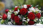 Red roses and white freesia in a bouquet, with greenery.