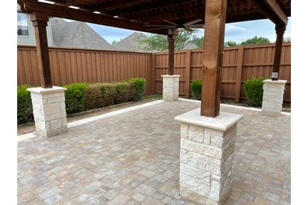 A person wearing work gloves places a large, light-colored stone to build a low wall on a gravel path.