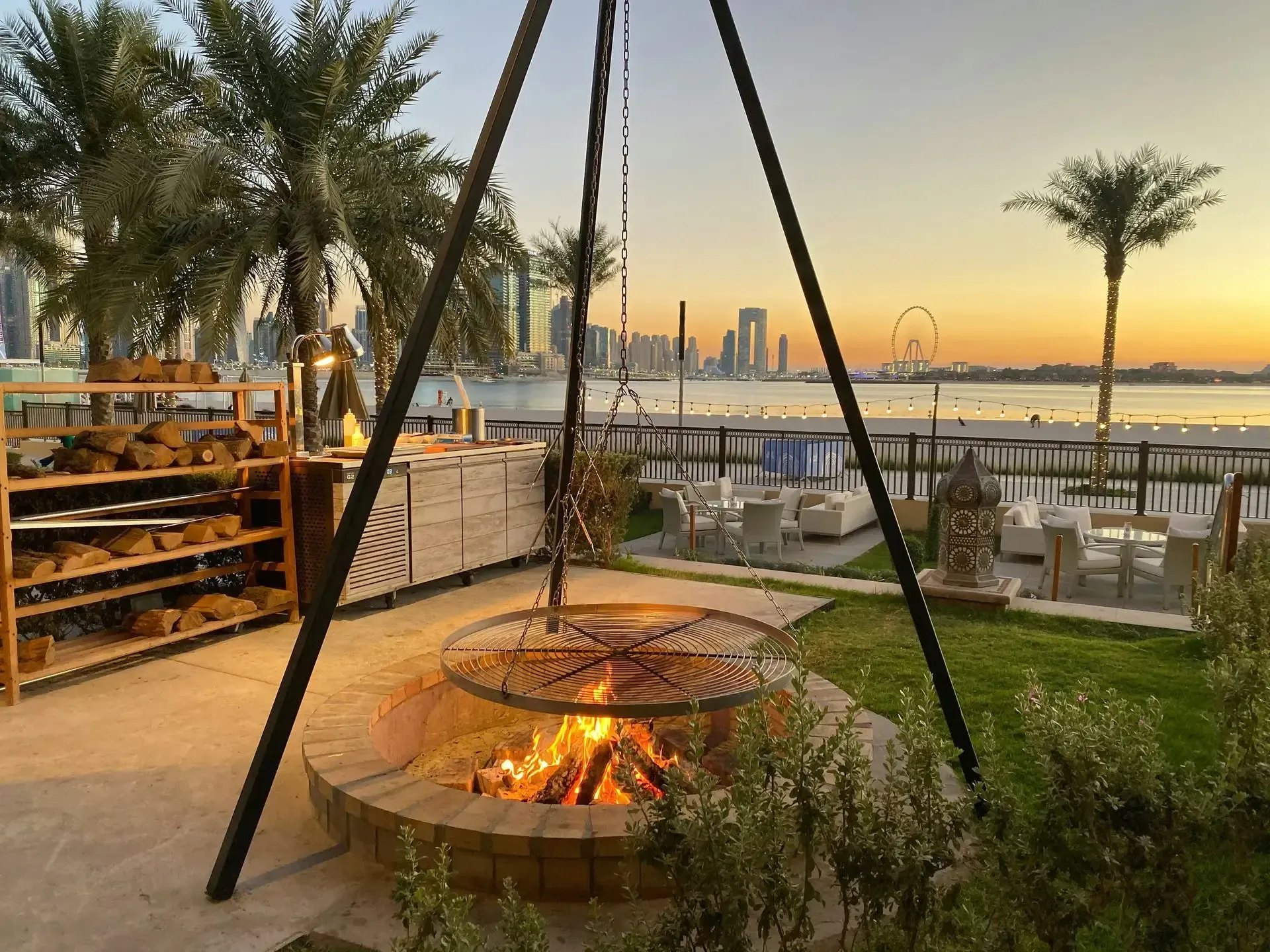 Fire pit with grill and a waterfront view at sunset.