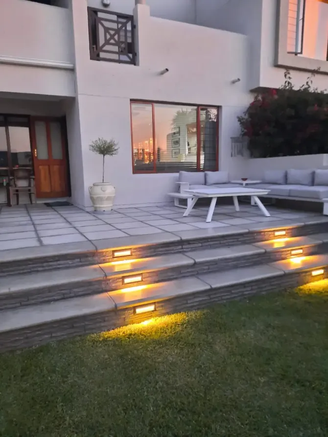 Patio with steps, lit by warm lights, leads to a seating area reflecting sunset.