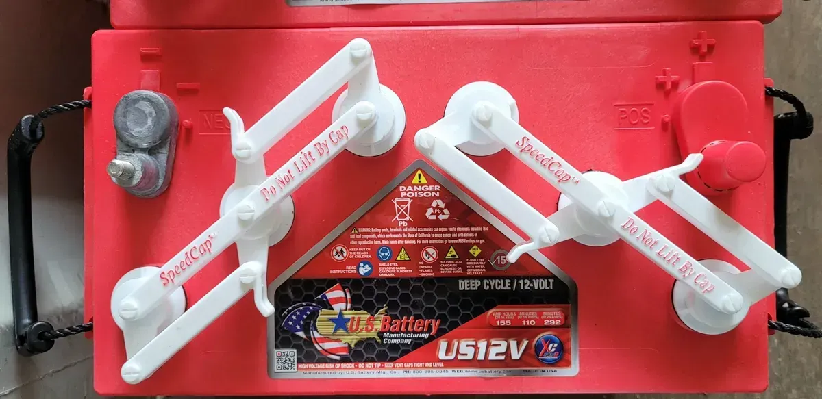 A red battery is sitting on top of a wooden table.