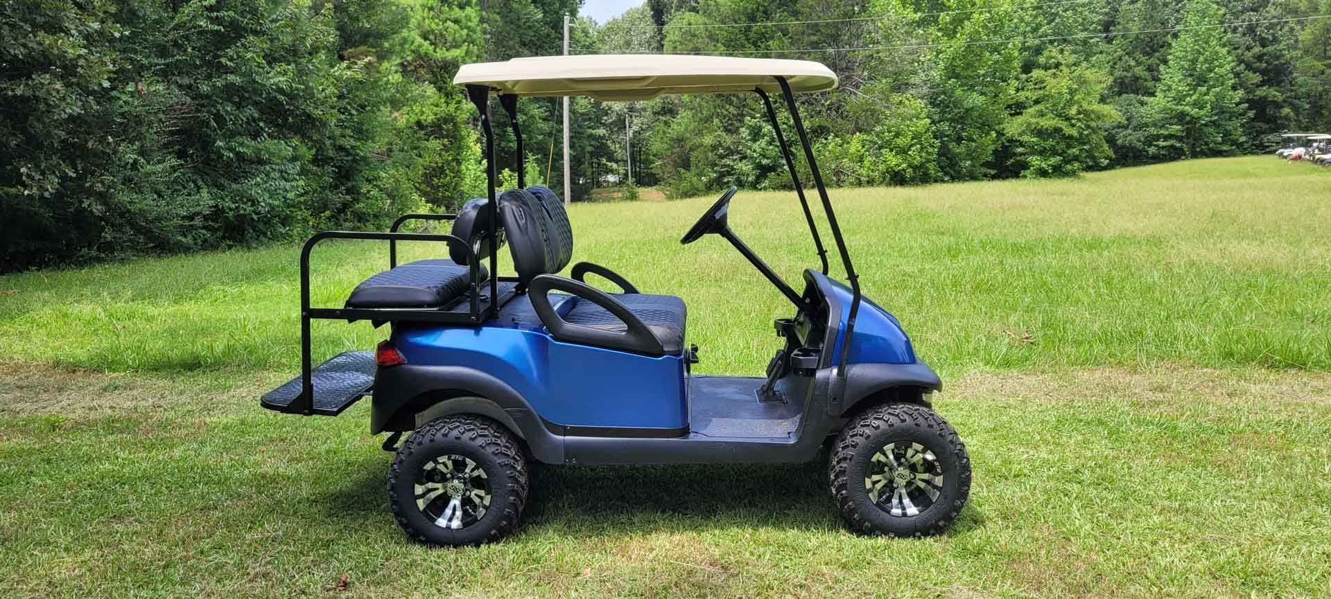 A blue golf cart is parked in a grassy field.