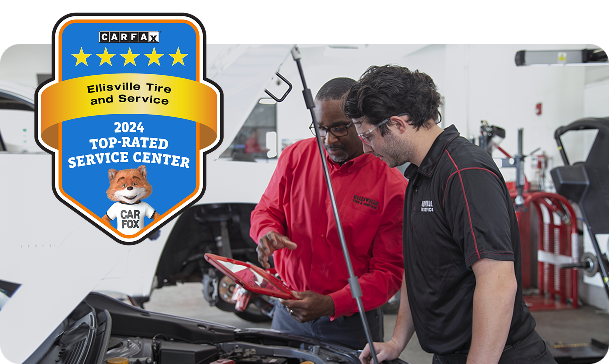 Two men are looking under the hood of a car. | Ellisville Tire And Service
