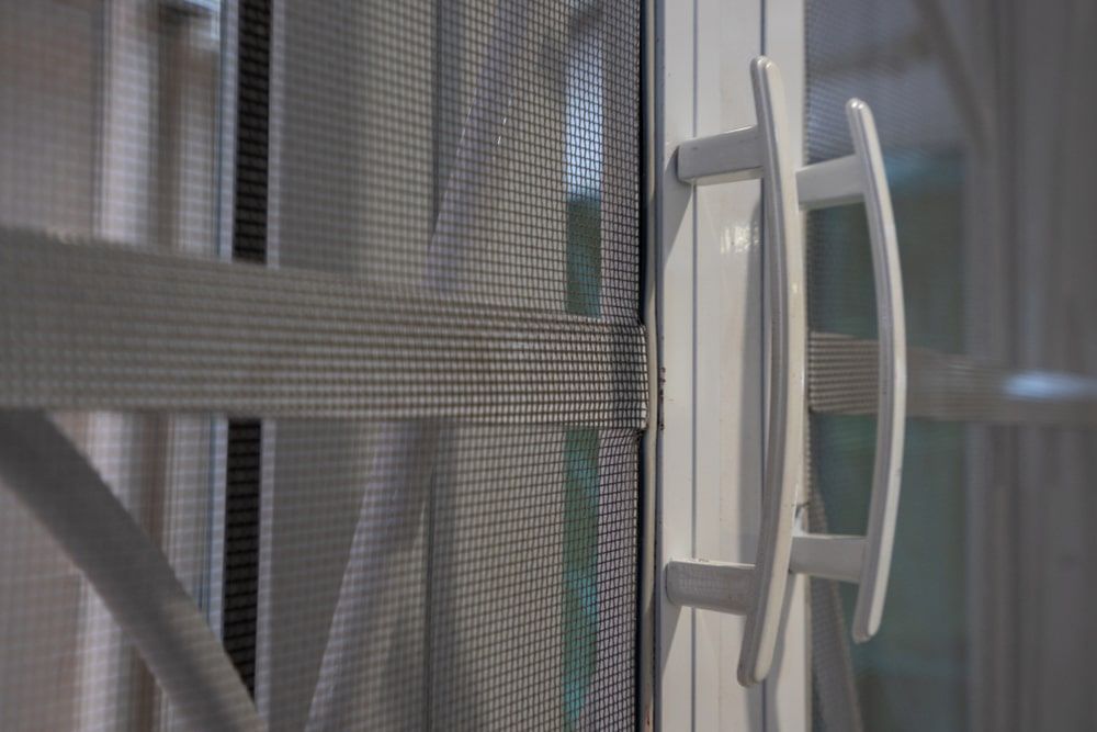 A Close Up Of A Sliding Screen Door With A Handle — Budget Home Improvements In Tweed Heads South, NSW