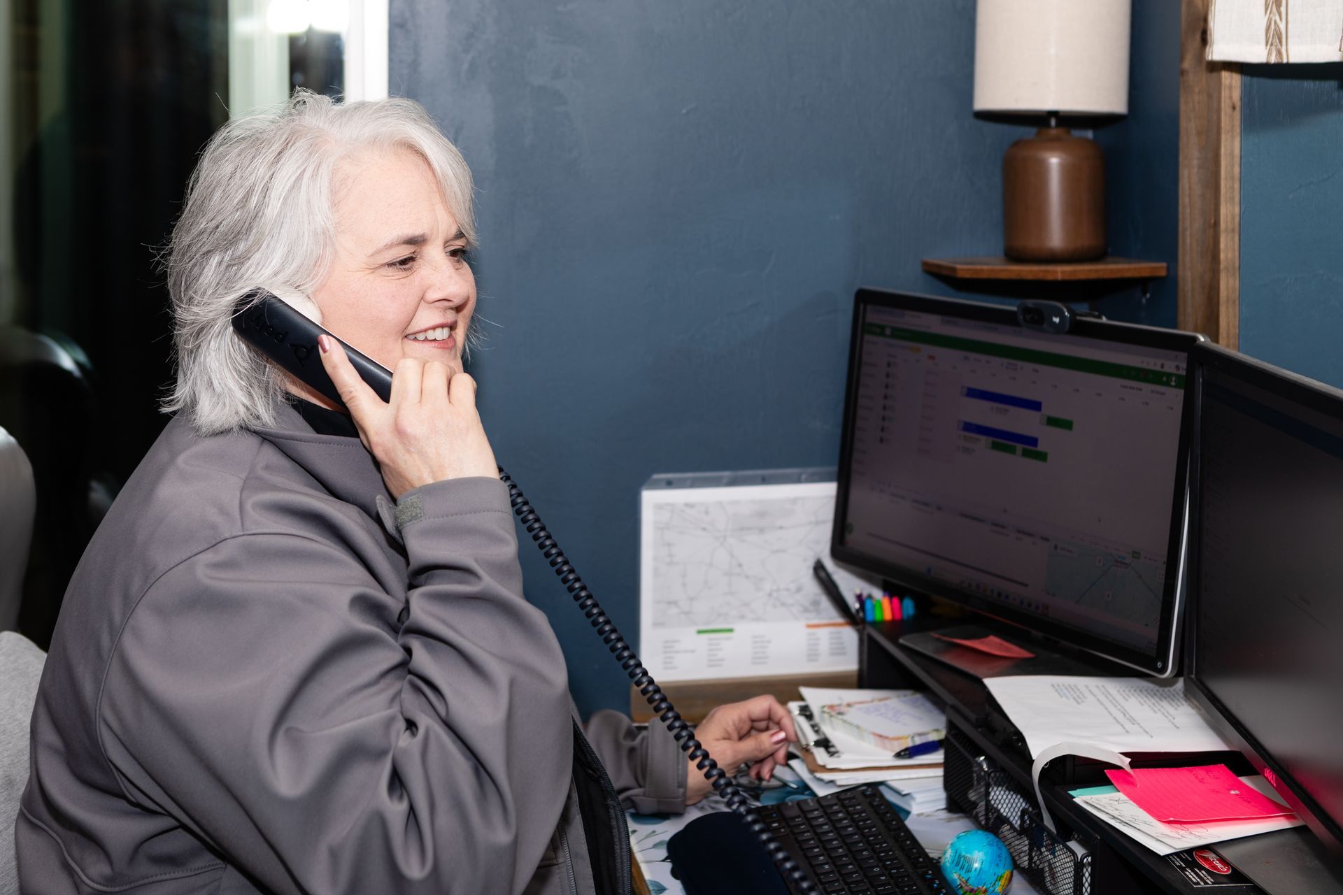 HVAC technician in cap and safety glasses inspects a unit outdoors, using a tablet. Toolbox in the foreground.
