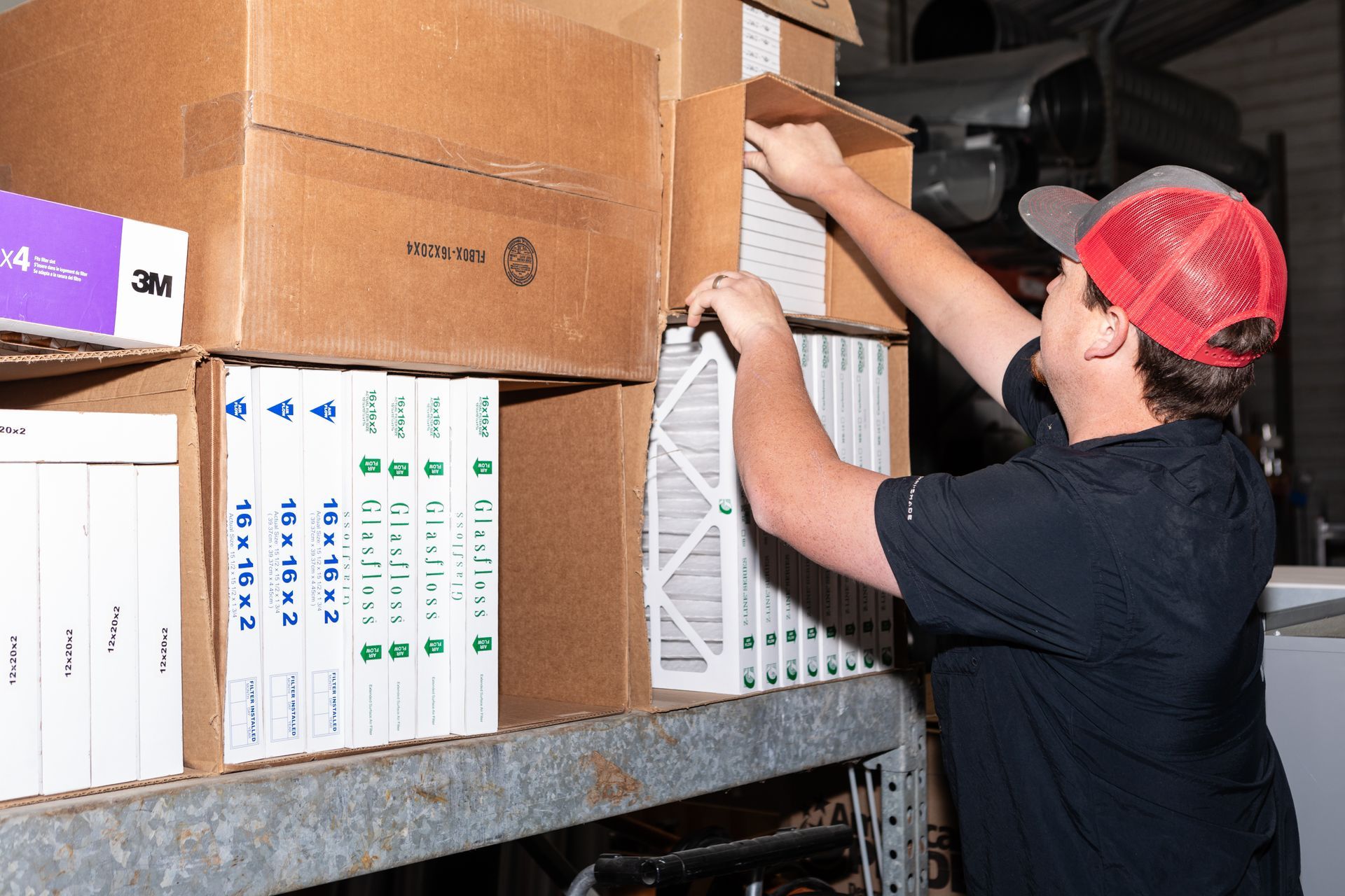 Hand replacing an air filter in a white housing. The filter is white with a grid pattern.