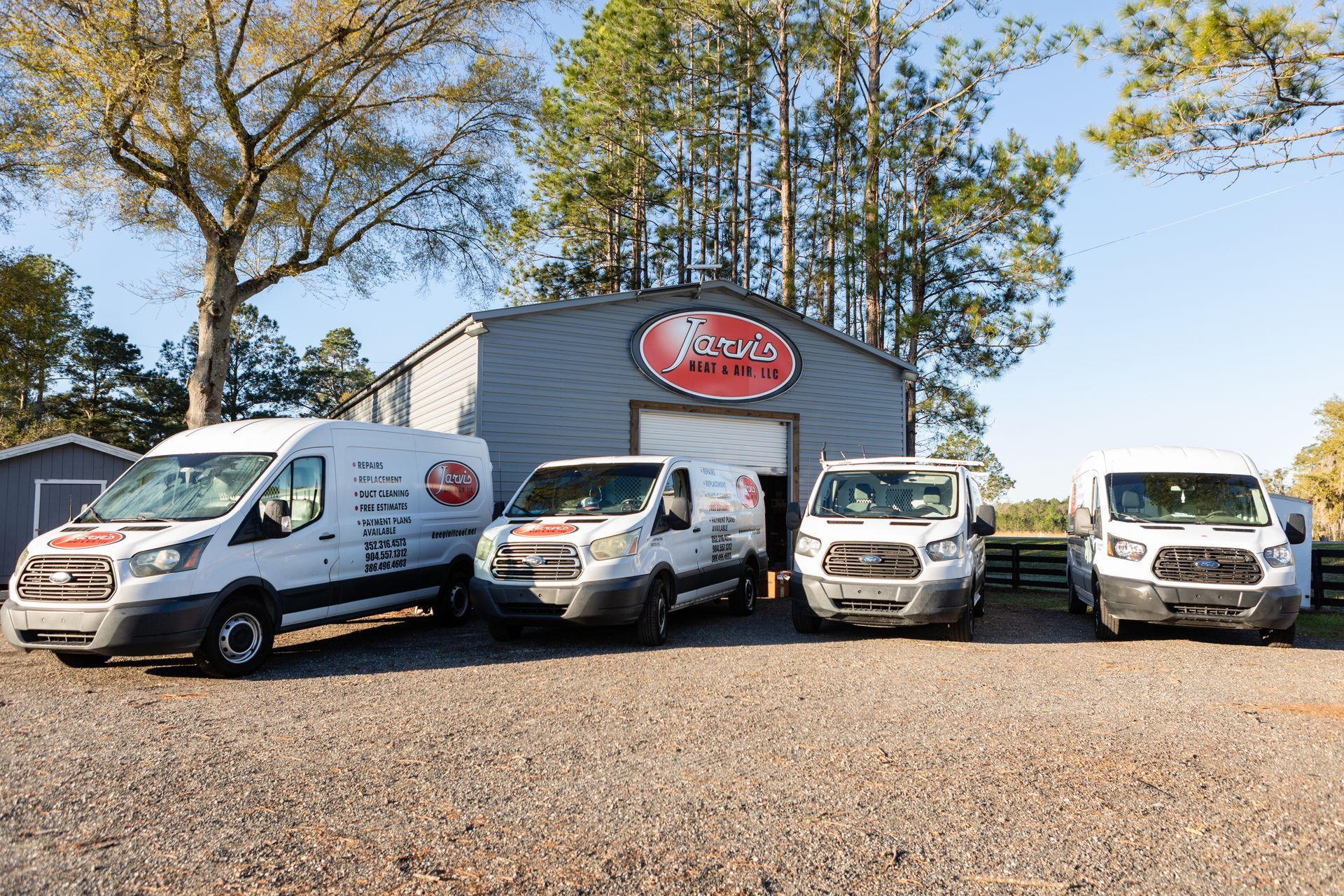 Street with parked cars, multi-story buildings of brick, white, and modern glass. Trees and blue sky.