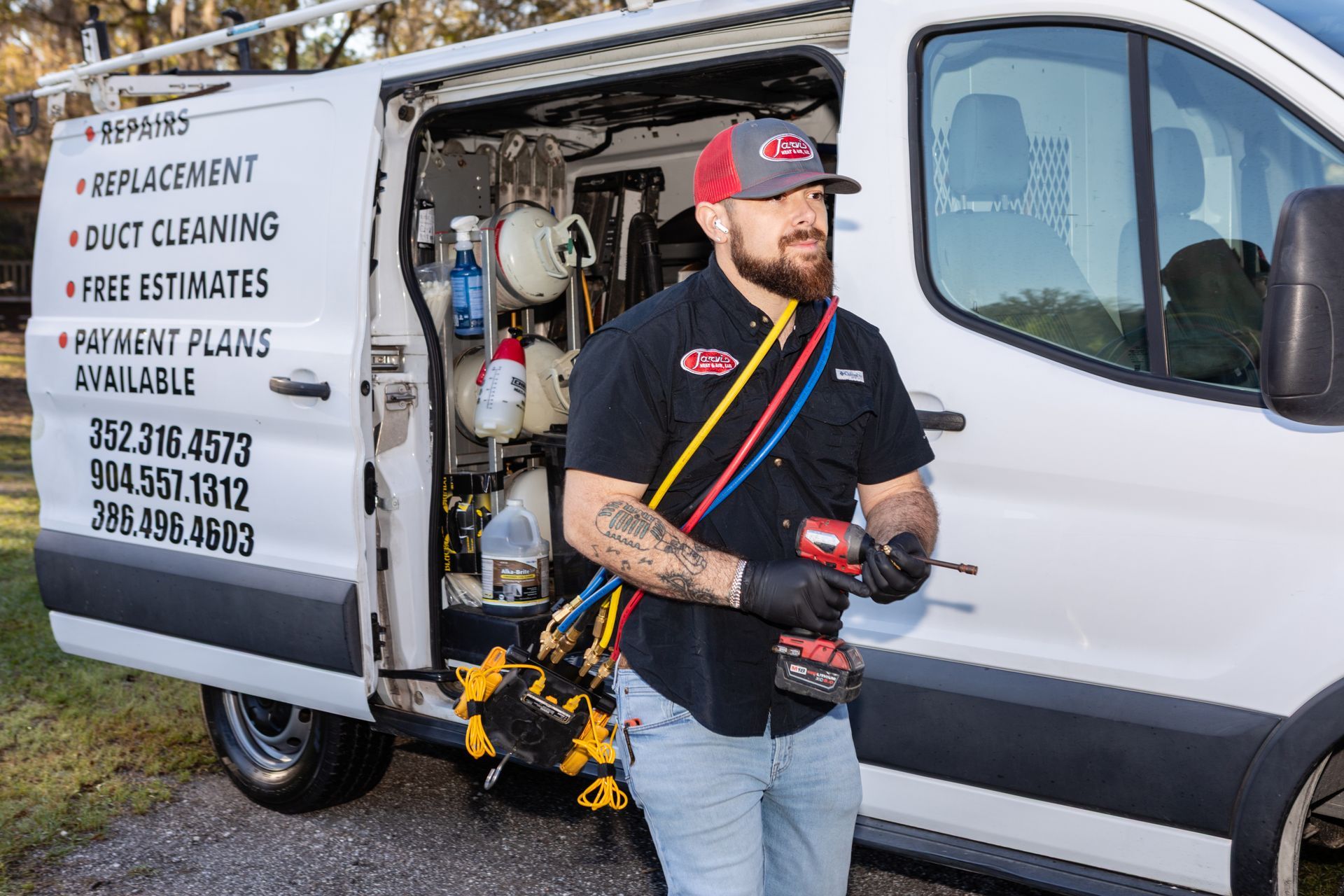 A technician in blue overalls tests an outdoor air conditioning unit with a multimeter.