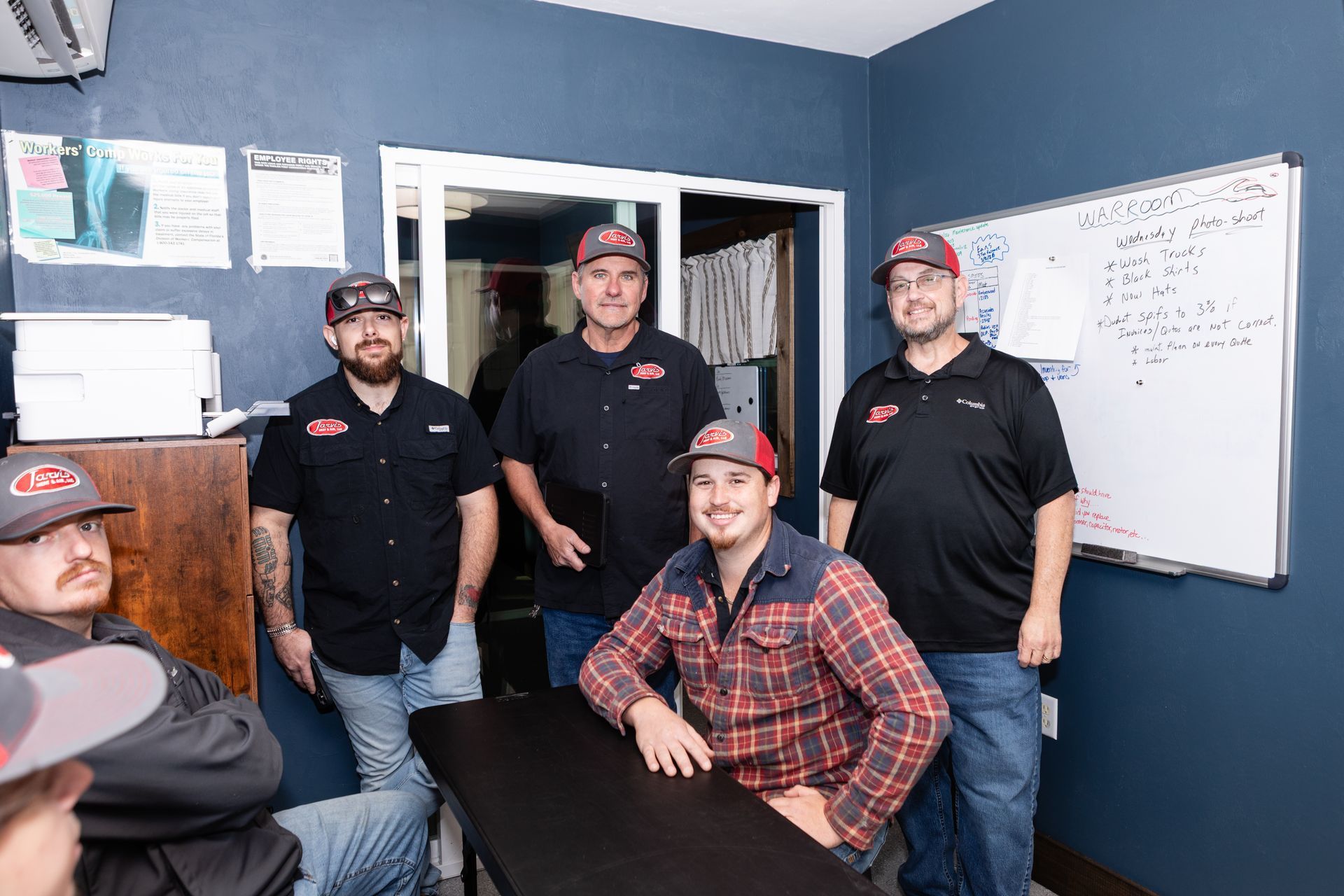 Person in a blue cap cleaning an air conditioner filter mounted on a white wall.