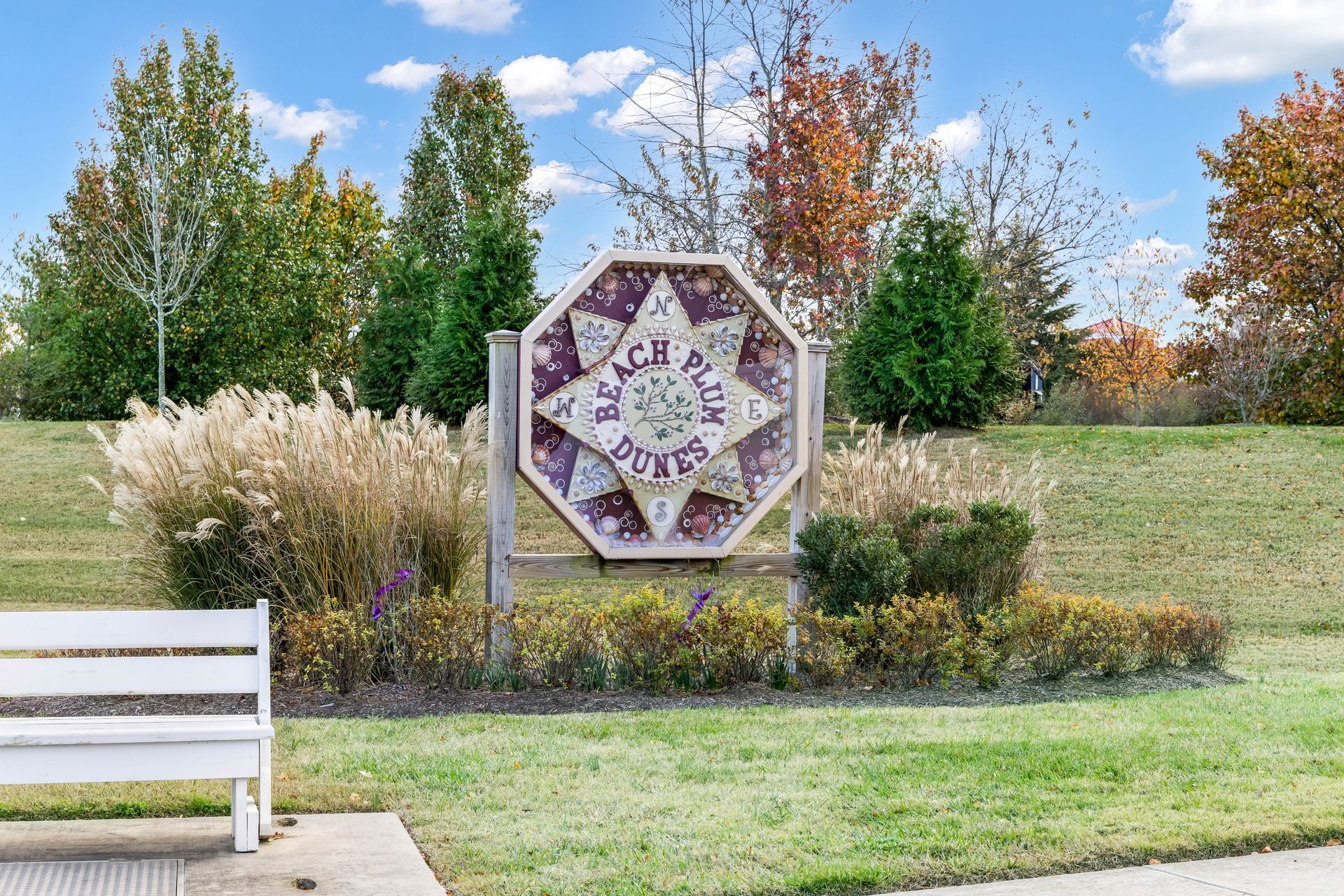 A white wooden bench sits before a decorative octagonal sign reading 