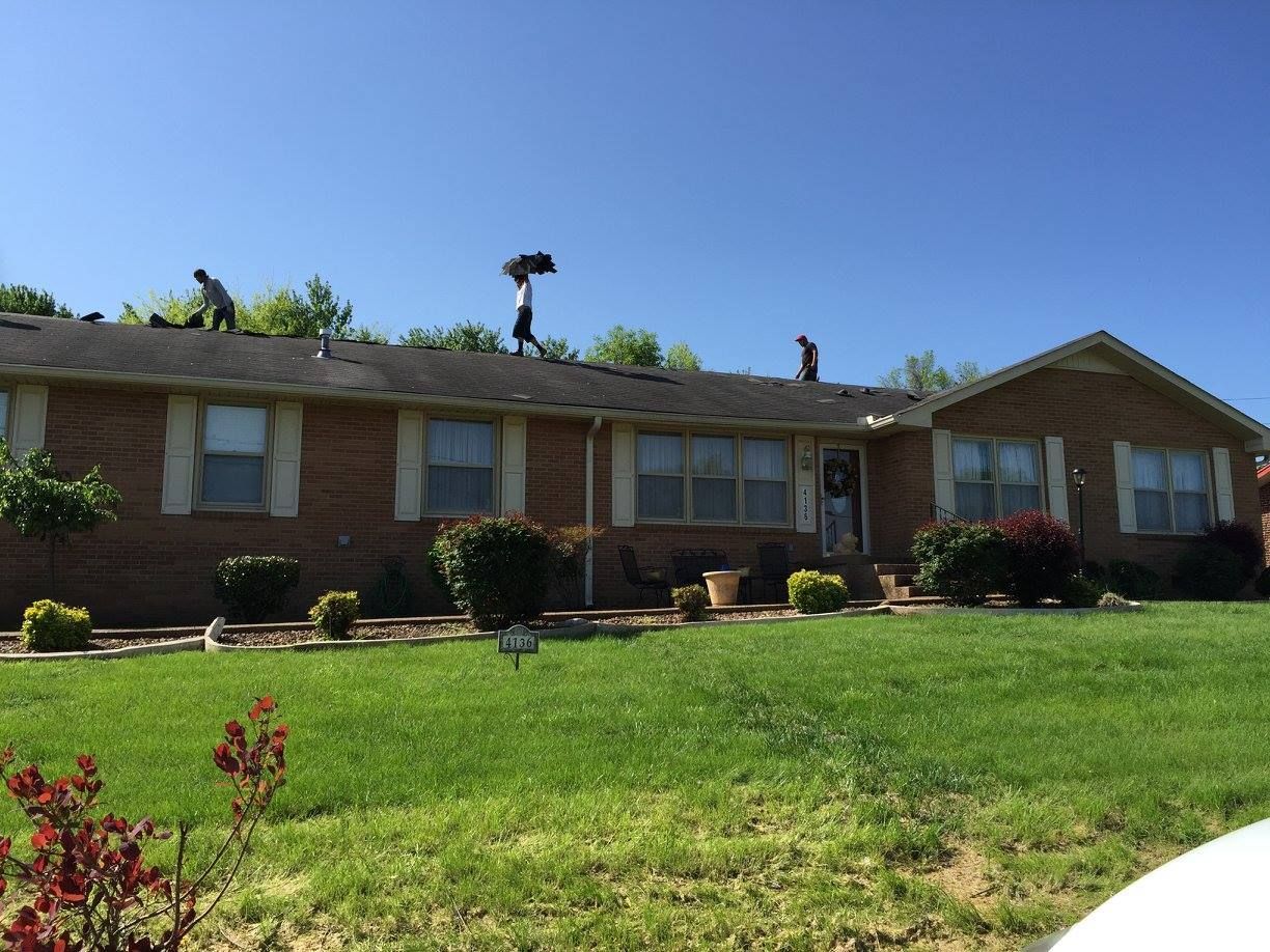 two men are working on the roof of a brick house