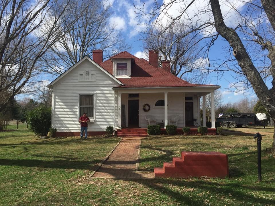 a man is standing in front of a white house with a red roof
