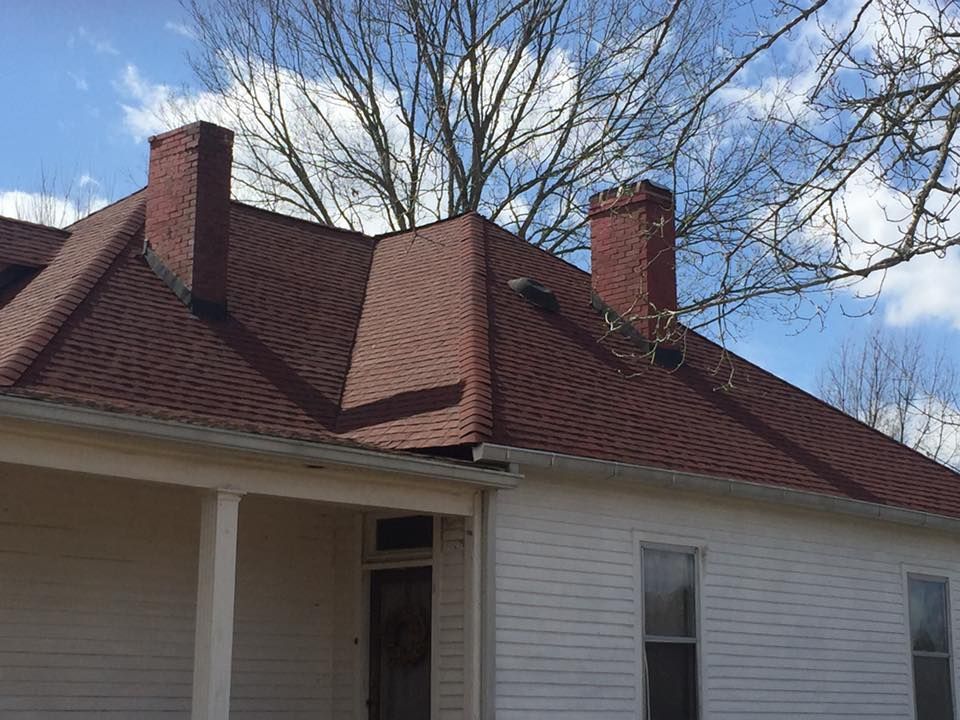 a white house with a red roof and chimneys