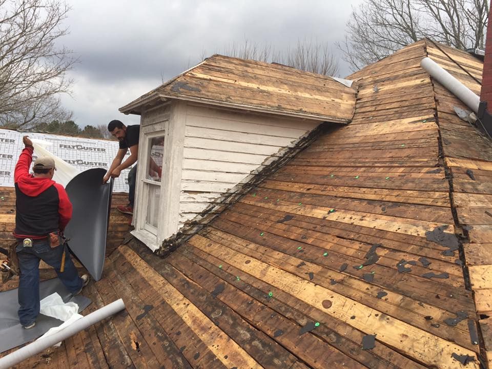 two men are working on the roof of a house