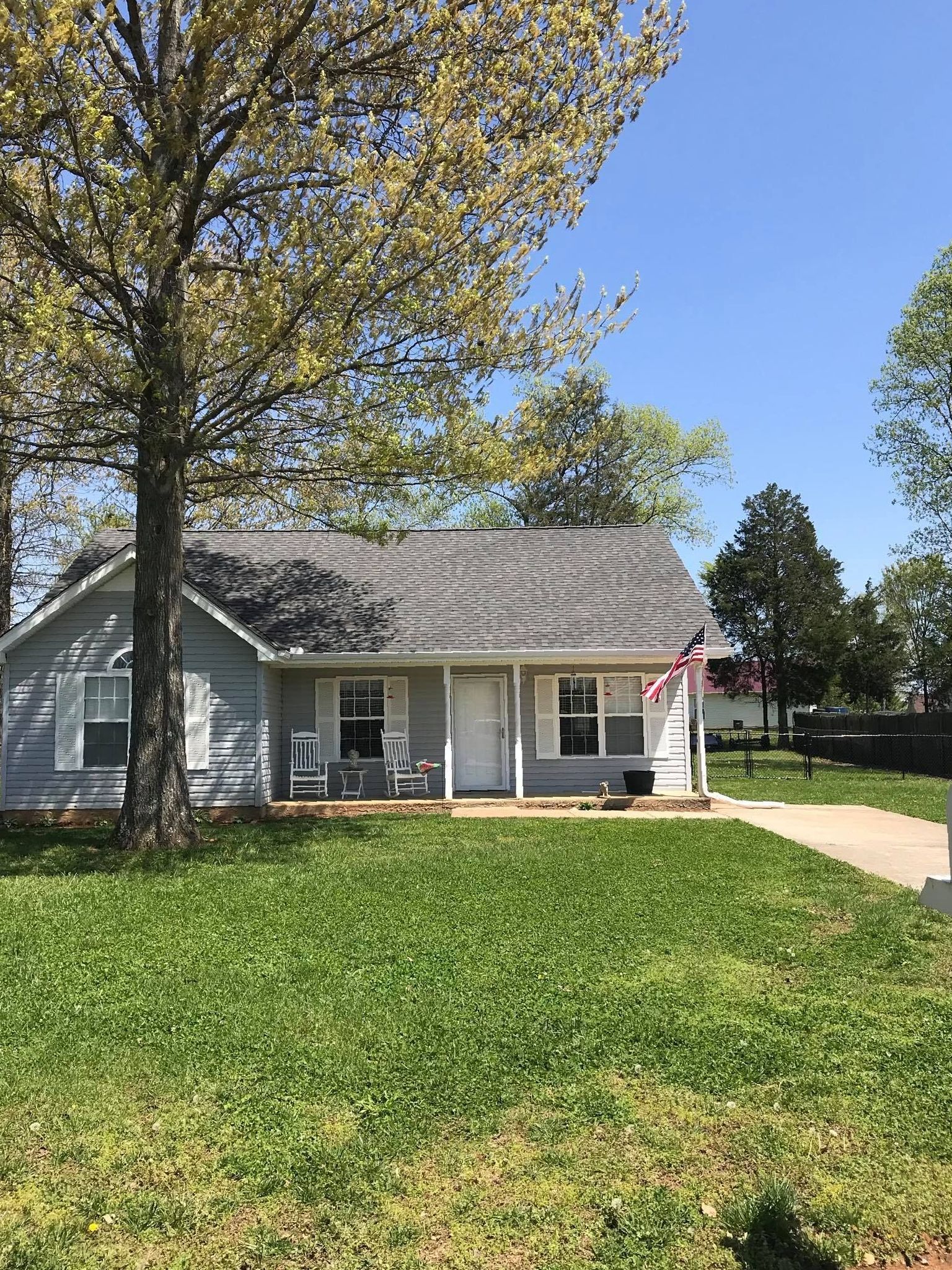 a small house with a porch and a large lawn in front of it