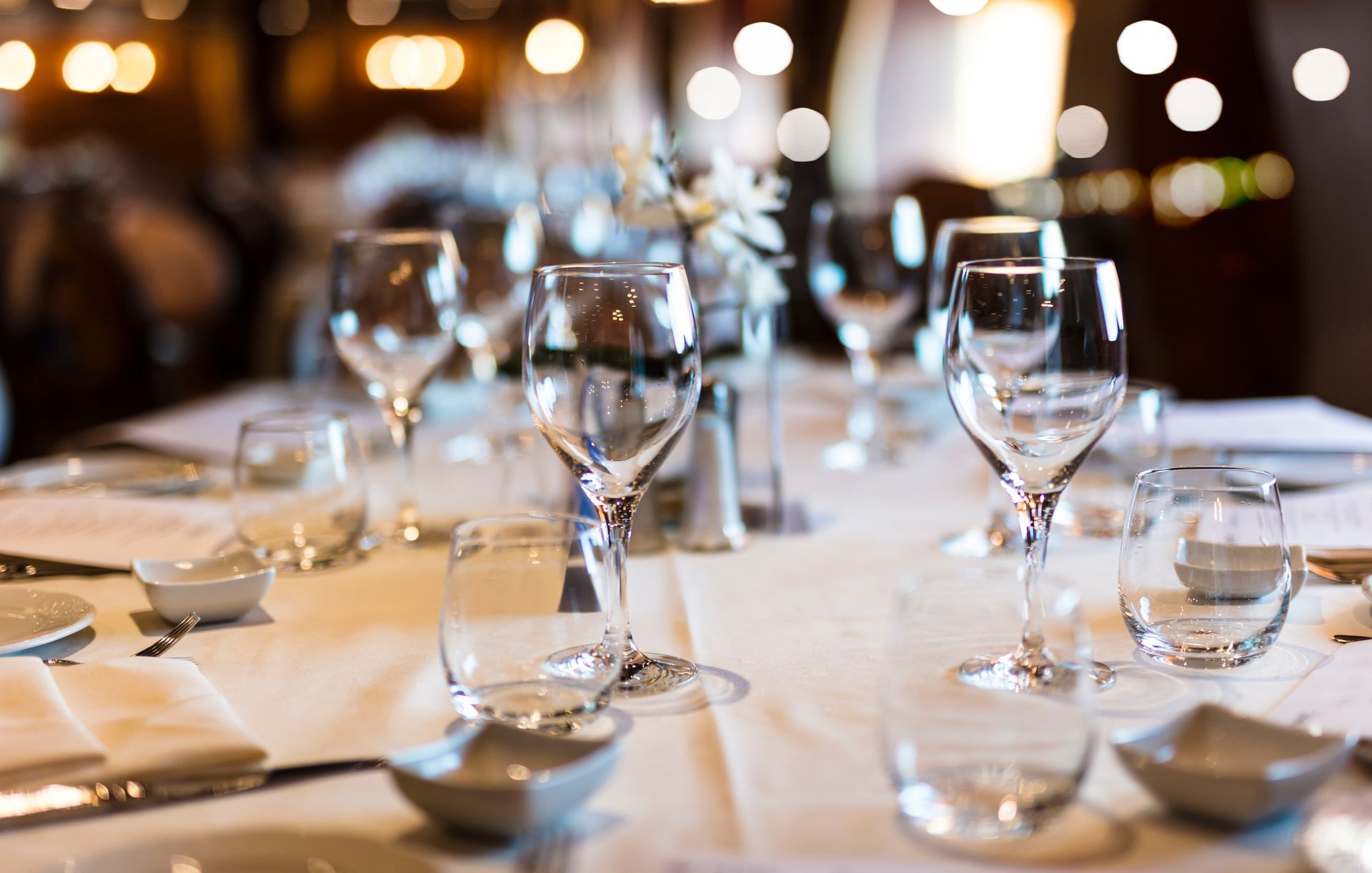 Elegant restaurant table set with glasses and place settings, blurred background.