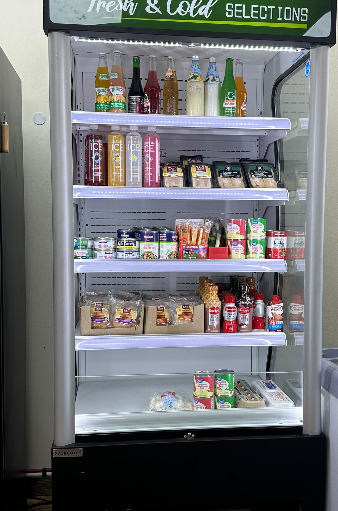 A refrigerated display case stocked with drinks and snacks in a store.