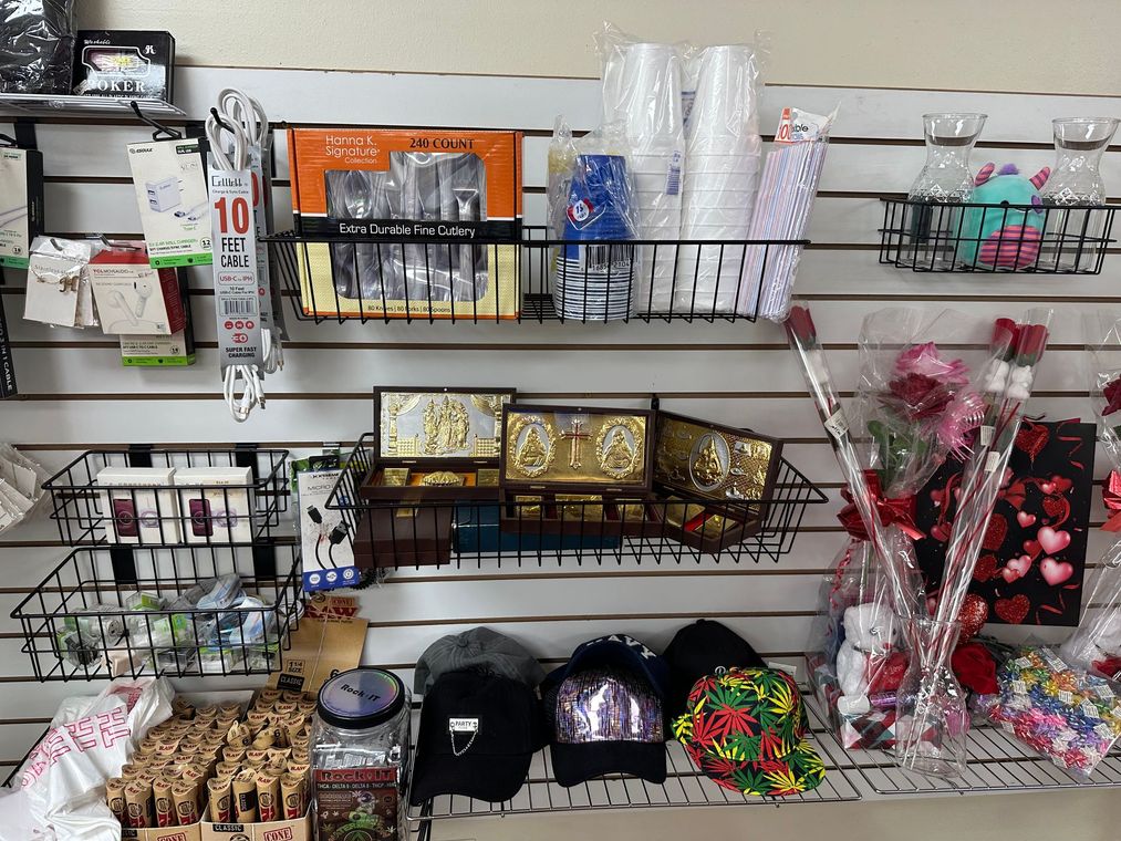 Shelves in a store display various items: cups, gifts, hats, and roses, arranged against a white slatted wall.