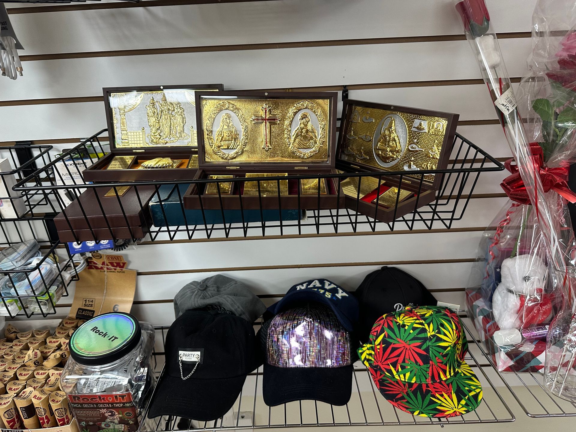 Hats and religious boxes in a shop. Hats are below, boxes are on a wire shelf.