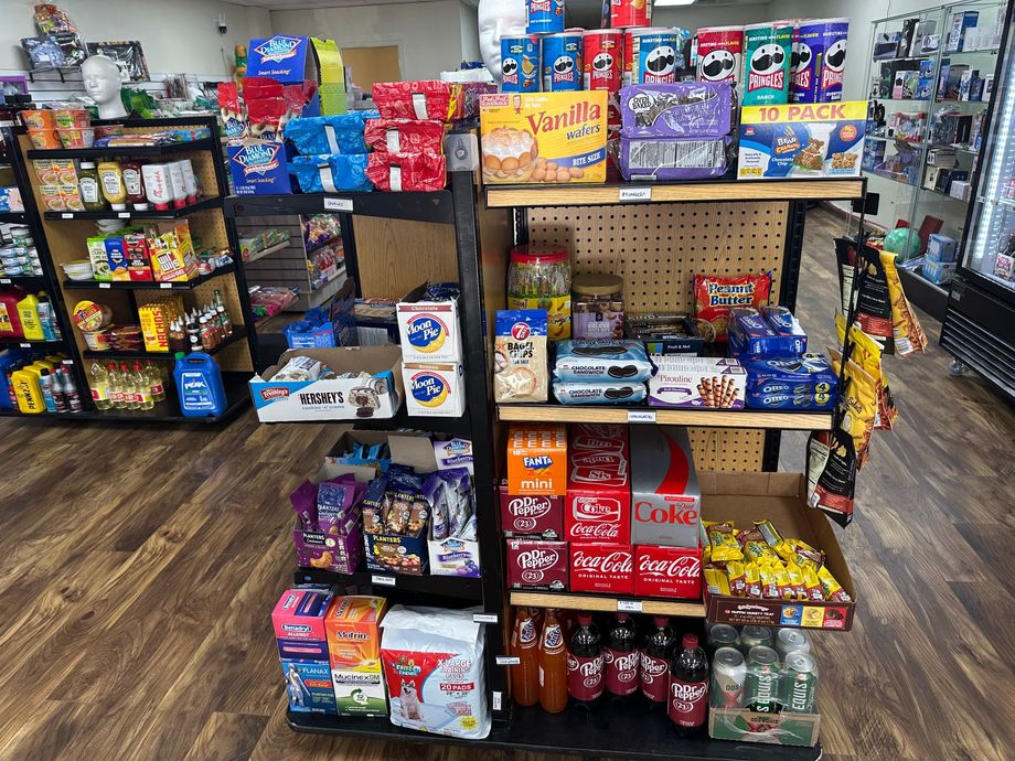 Snack display in a store, featuring chips, cookies, soda, and other treats on shelves with wooden flooring.