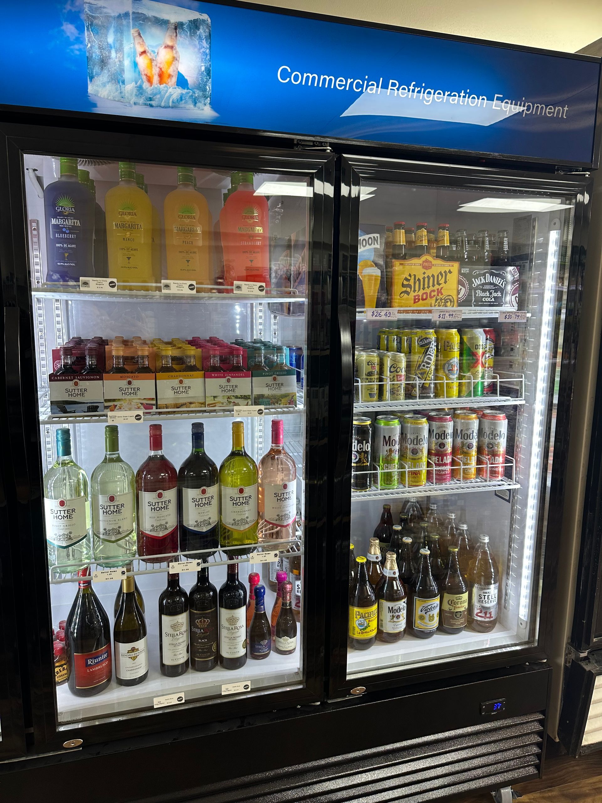 Refrigerated display case filled with drinks: colorful bottles, cans, and other beverages.