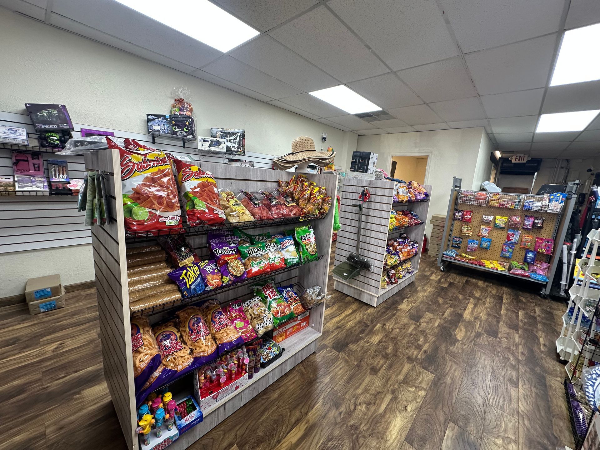 Inside a convenience store, snack shelves are stocked with chips and candy.