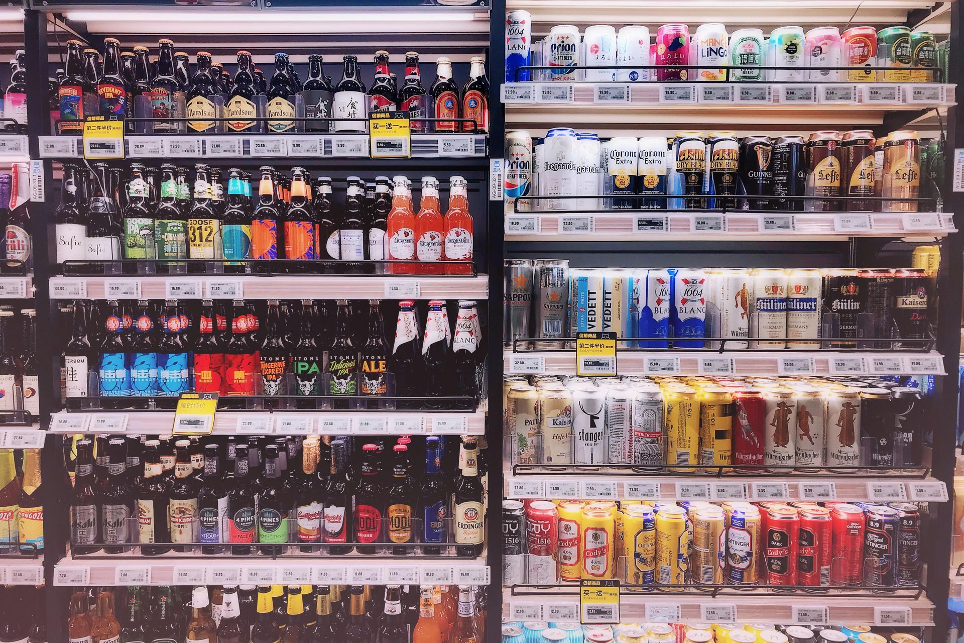 Shelves stocked with colorful beer bottles and cans in a brightly lit convenience store.