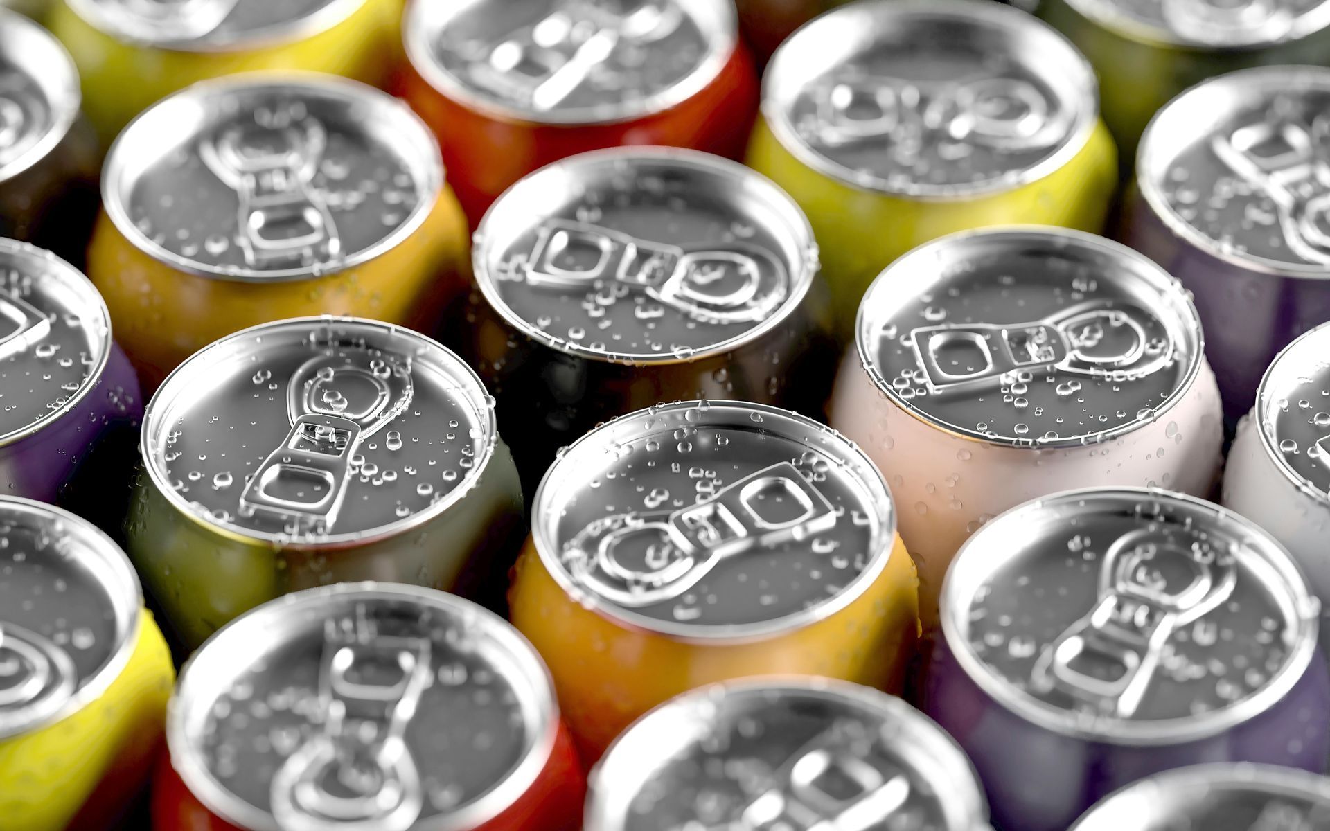 Close-up of colorful soda cans, silver tops, with condensation droplets.