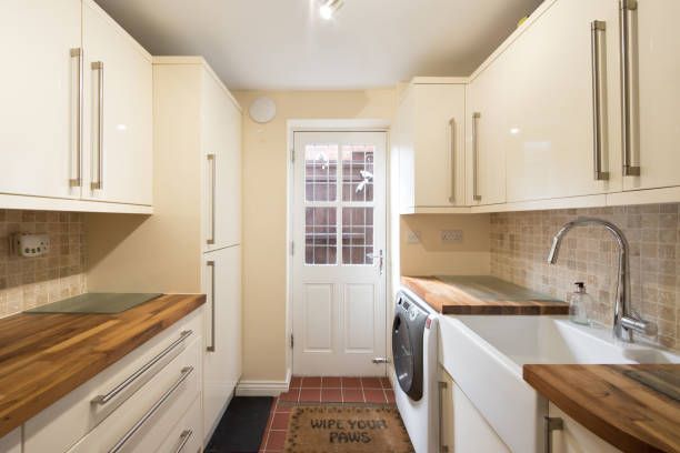 Small kitchen with white cabinets, wooden countertops, and a door at the end.