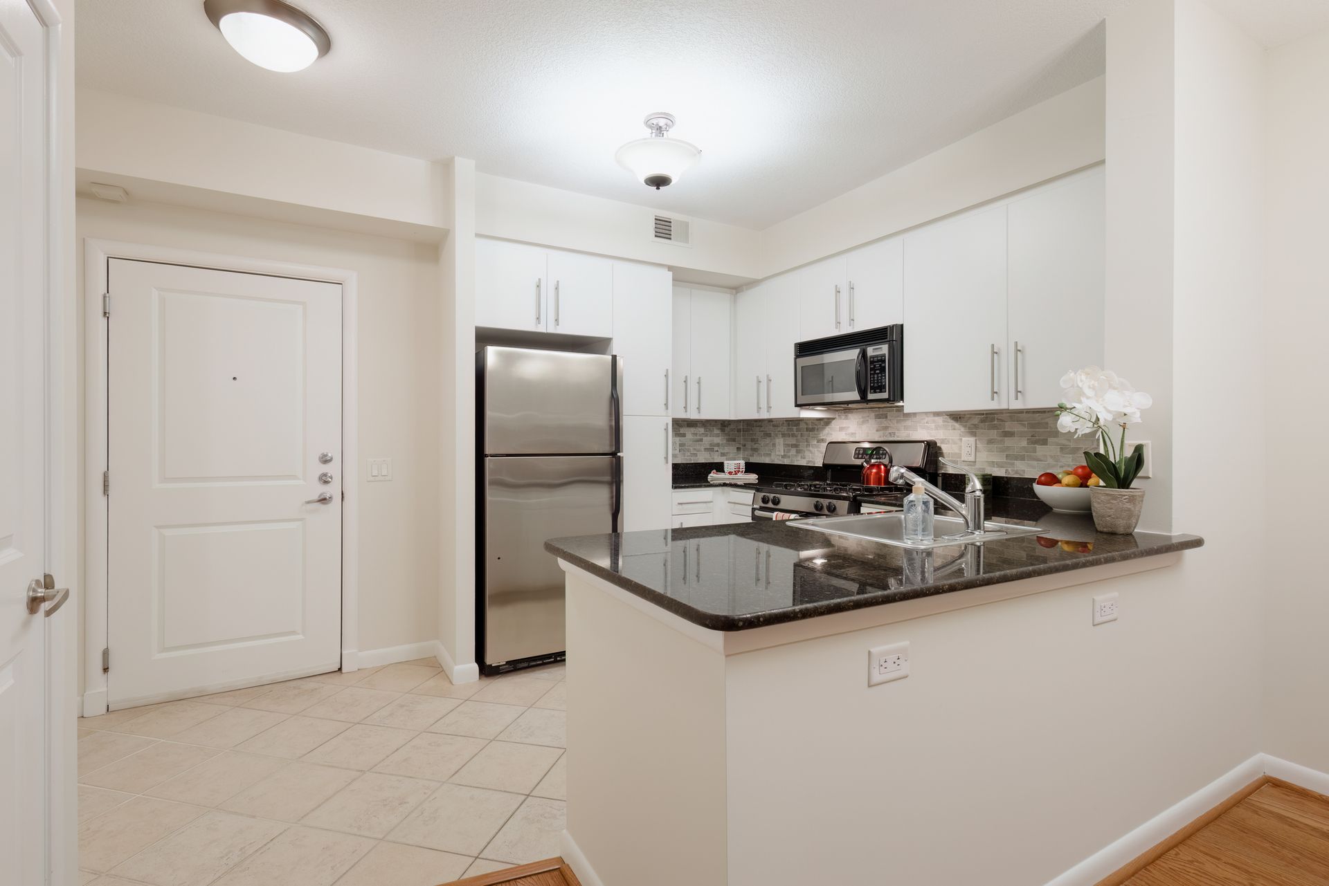 Modern kitchen with white cabinets, stainless steel appliances, and dark granite countertops.