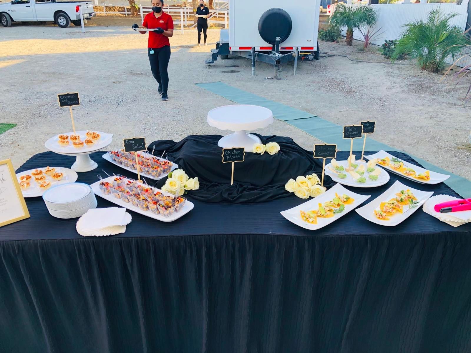 A table with plates of food on it and a man standing behind it.