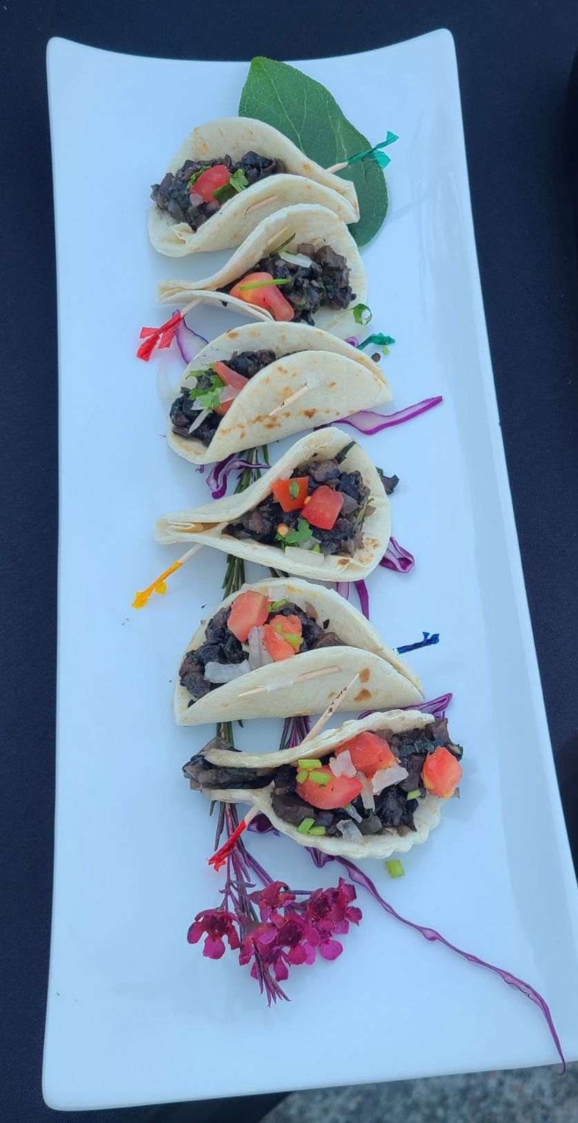 A white plate topped with tacos and vegetables on a table.