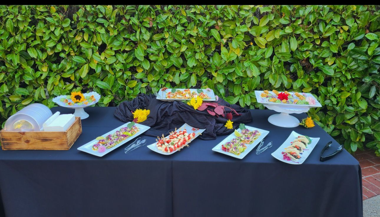 A table with plates of food on it and a black table cloth.