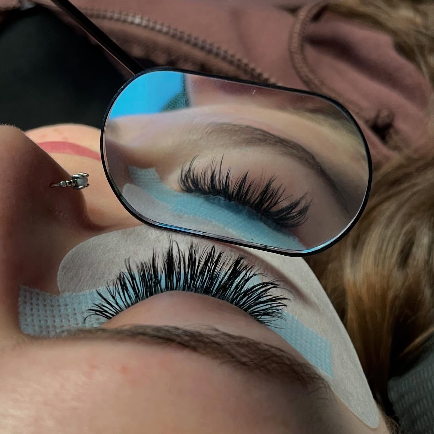 A woman is looking at her eyelashes in a mirror