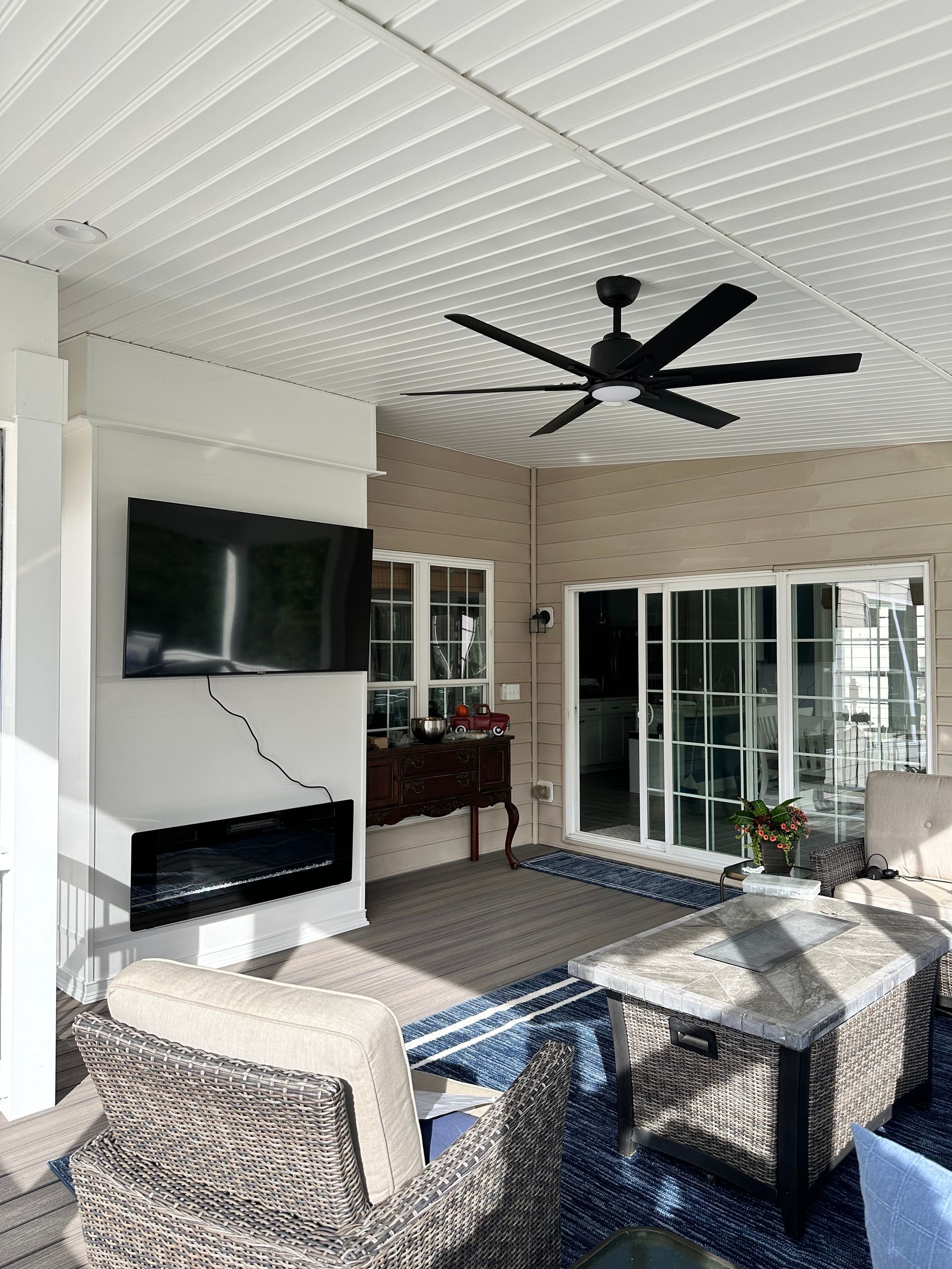 A living room with a ceiling fan and a flat screen tv.