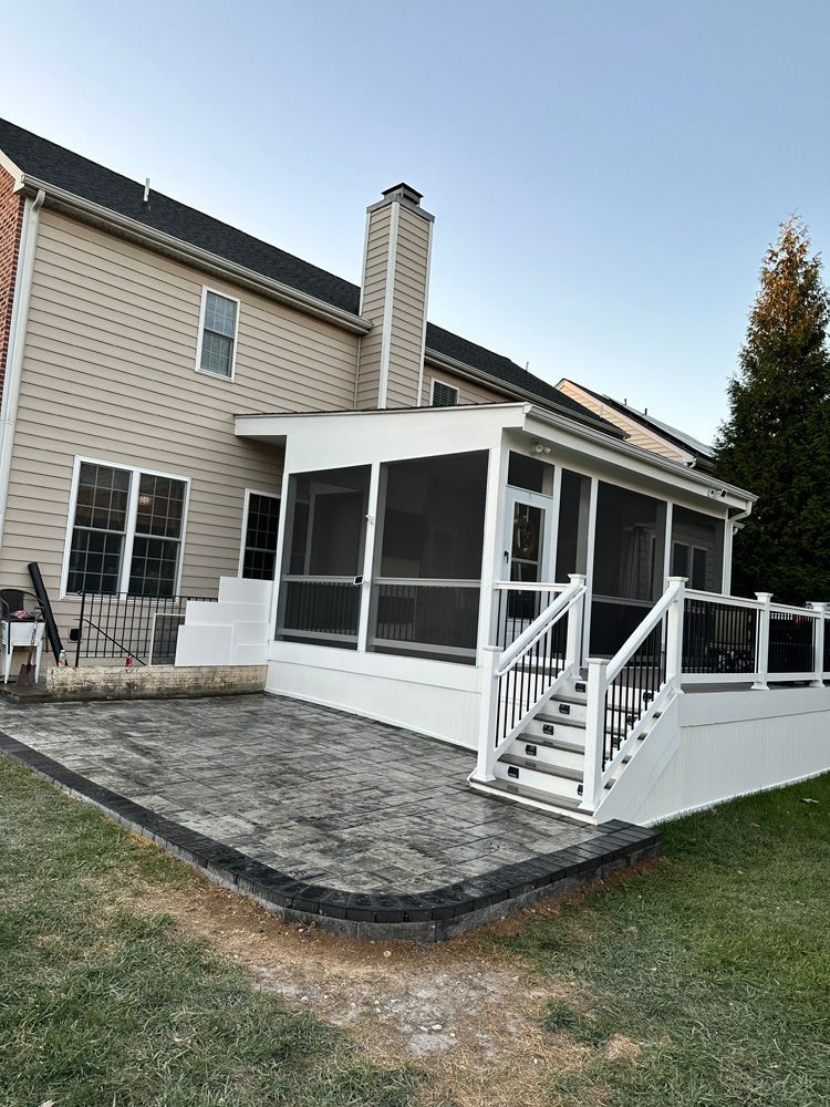 A screened in porch with stairs and a patio in front of a house.