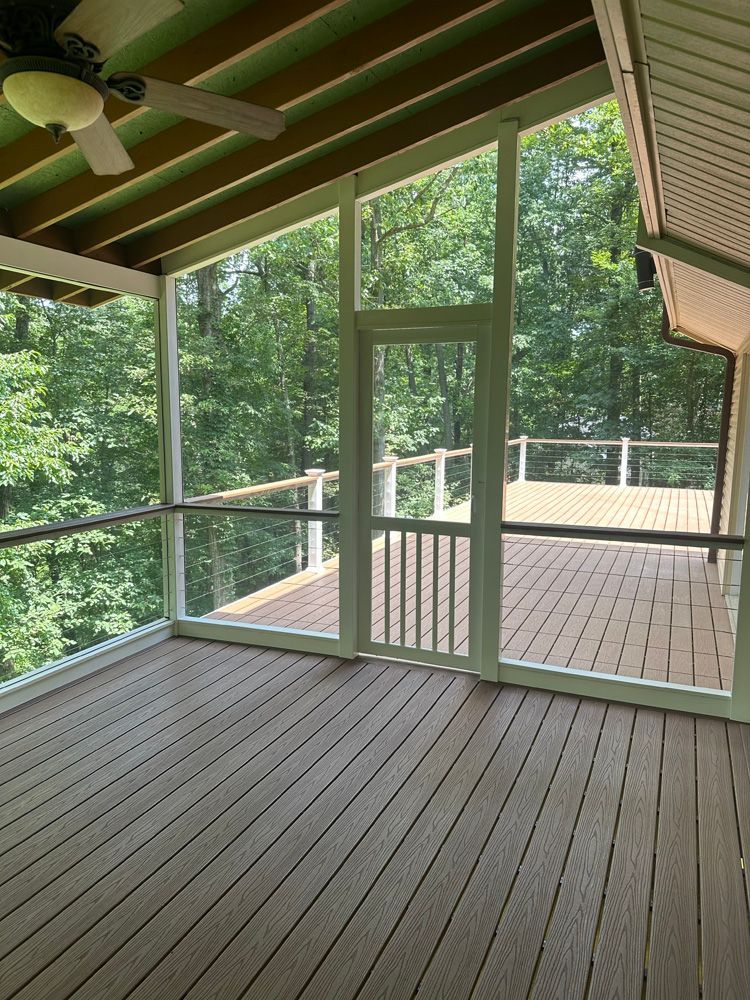A screened in porch with a wooden deck and a ceiling fan.