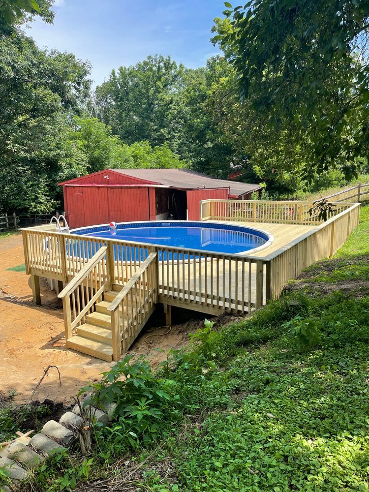 A large swimming pool with a wooden deck in front of a house.