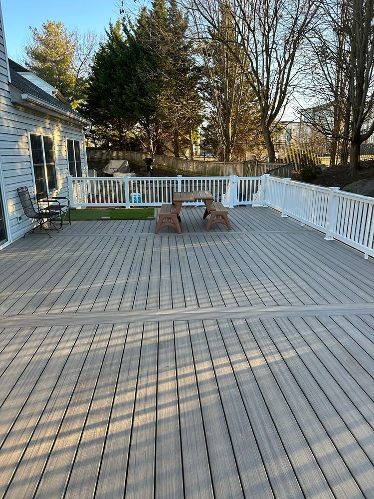A large deck with a picnic table and chairs on it.