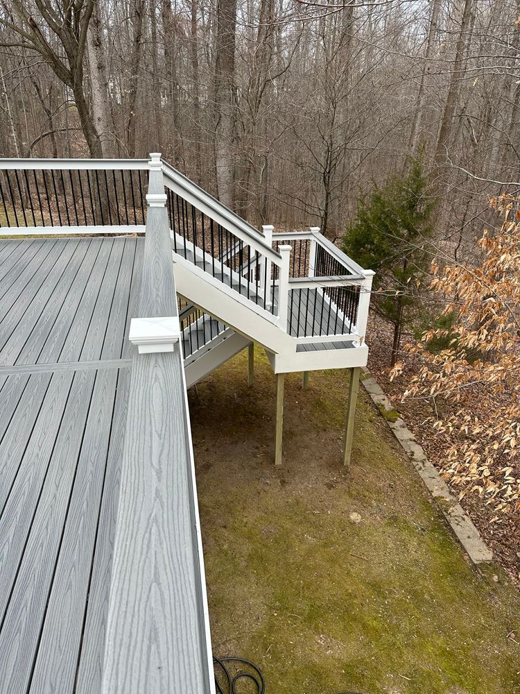 A deck with stairs leading up to it in the woods.