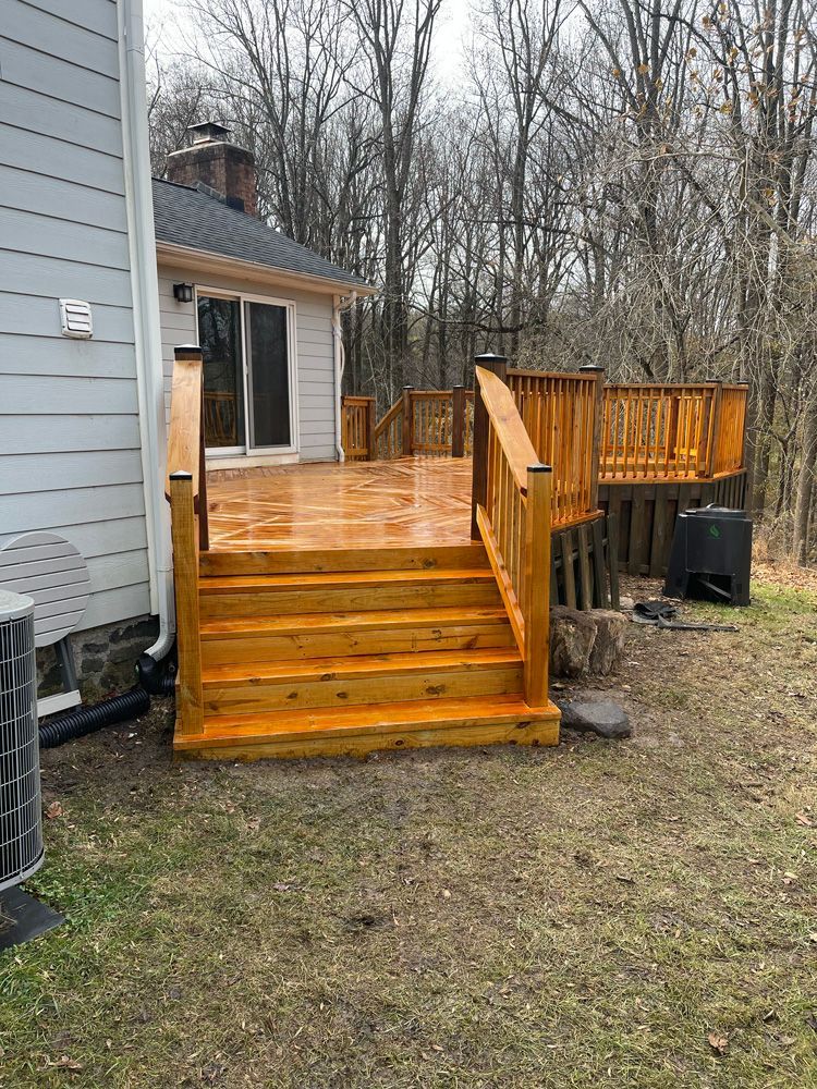 A wooden deck with stairs leading up to it is in the backyard of a house.